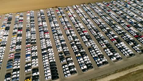 aerial footage of finished cars ready to be shipped on huge distribution center