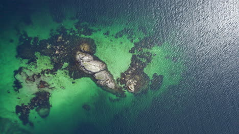 劇烈的空中俯<unk>鳥眼景觀 岩石島的綠色海洋,波浪,沙底和太陽的閃光在水的波浪