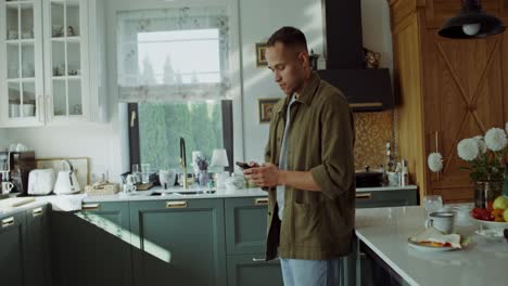 hombre usando el teléfono en la cocina