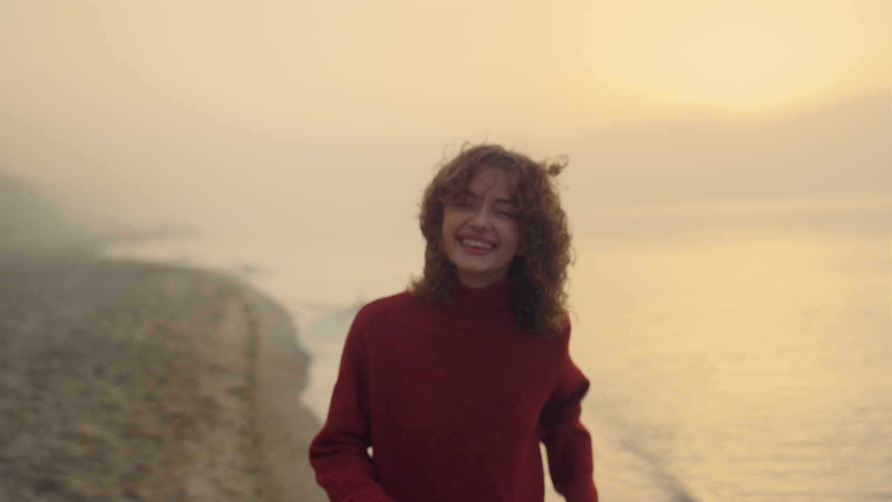 Gün doğumunda okyanus sahilinde dans eden mutlu kız. Sahil şeridi boyunca koşan kadın.