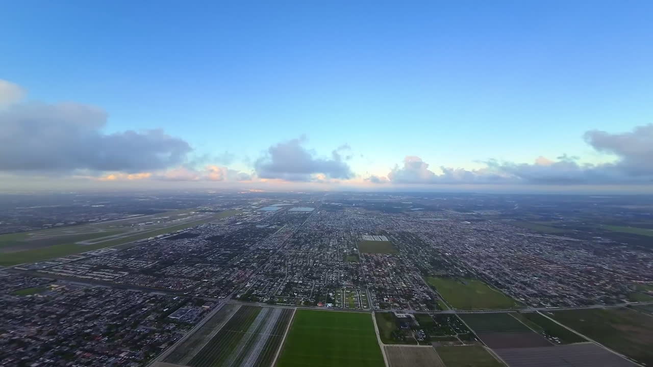 Flight among and over the light clouds. FPV drone footage above the vast urban landscape at daytime.