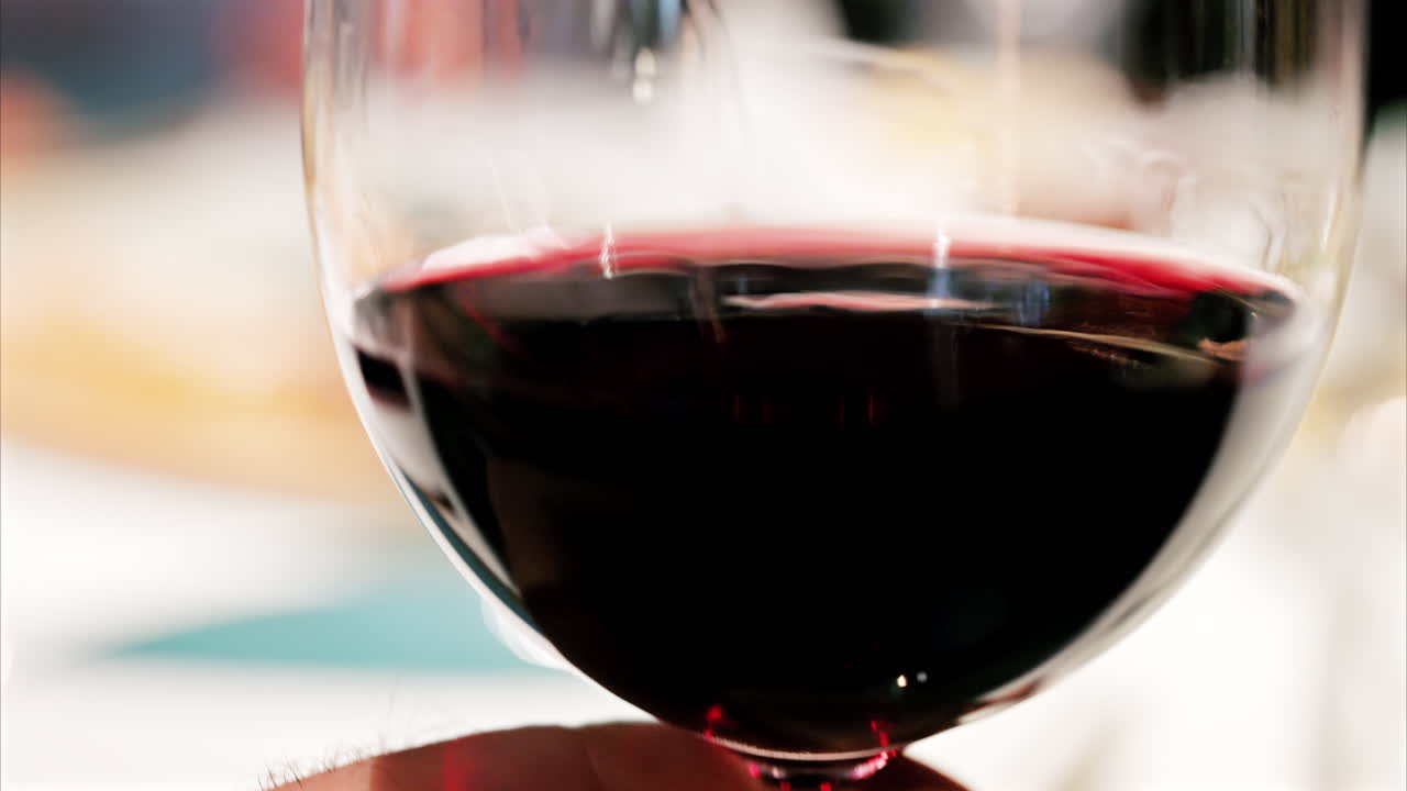 Primo piano di un bicchiere di vino rosso che viene fatto roteare per mostrare il suo ricco colore rubino