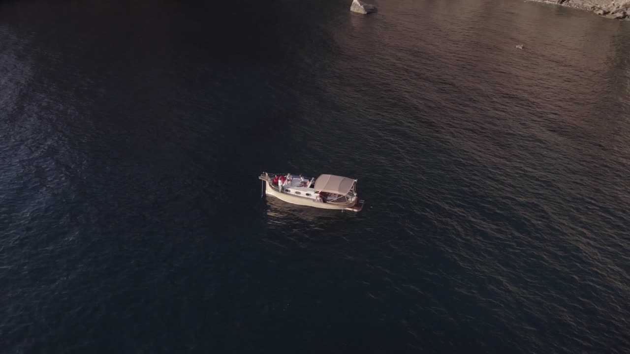 Small boat anchored in the ocean, aerial top down view