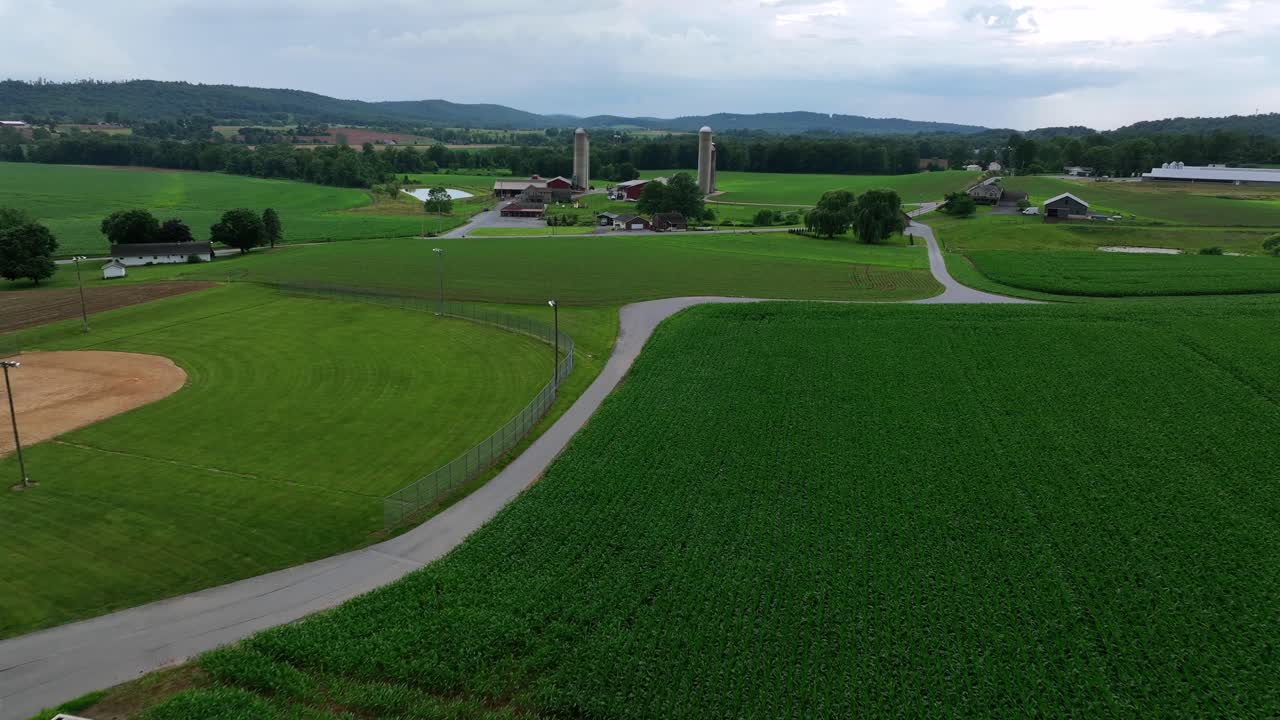American farmstead with barns and silo storages. Rural area with fields and neighborhoods. Summer day in USA. Aerial landing flight