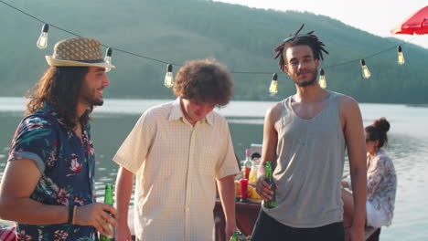 portrait of happy male friends at lake party