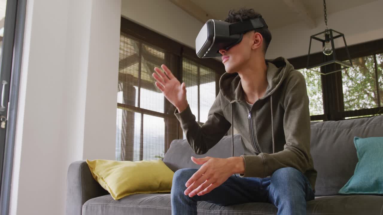 muchacho adolescente de dos razas usando auriculares vr en casa, cámara lenta