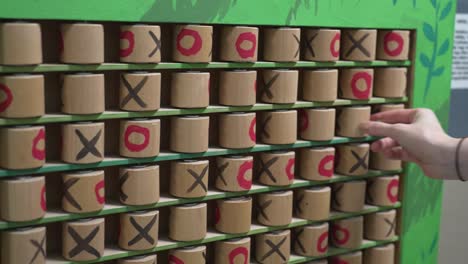 hand, die ein tic-tac-toe-spiel auf einem holzbrett dreht