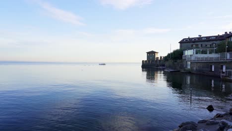 tranquil scene on the shores of lake garda with tourists enjoying the beach and fortification of the water castle in sirmione