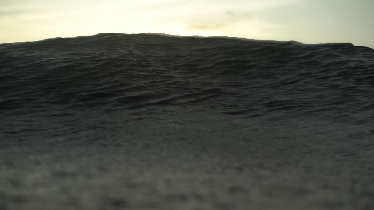 파도가 인도네시아 수중 카메라 위로 굴러가는 동안 밝은 플레어가 있는 슬로우 모션 샷 바다 표면