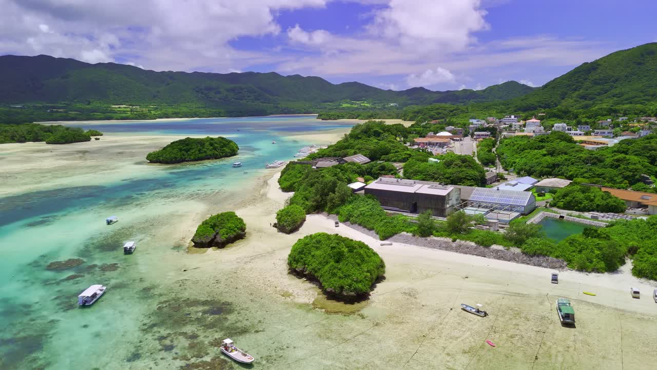 Aerial drone footage pans over the stunning turquoise waters and green islets of Kabira Bay, Ishigaki, Okinawa, Japan. A beautiful, sunny day in a tropical paradise with tour boats below