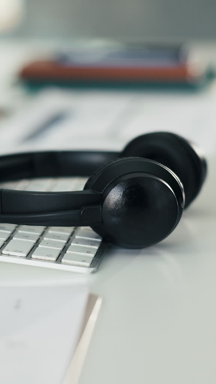 Auriculares negros apoyados sobre un teclado de ordenador blanco en un escritorio