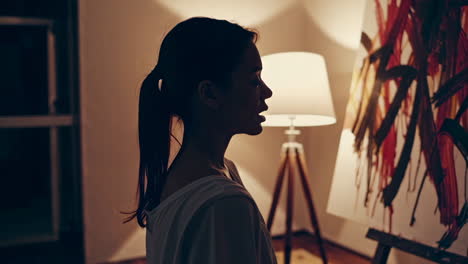 woman viewing abstract painting in a studio at night