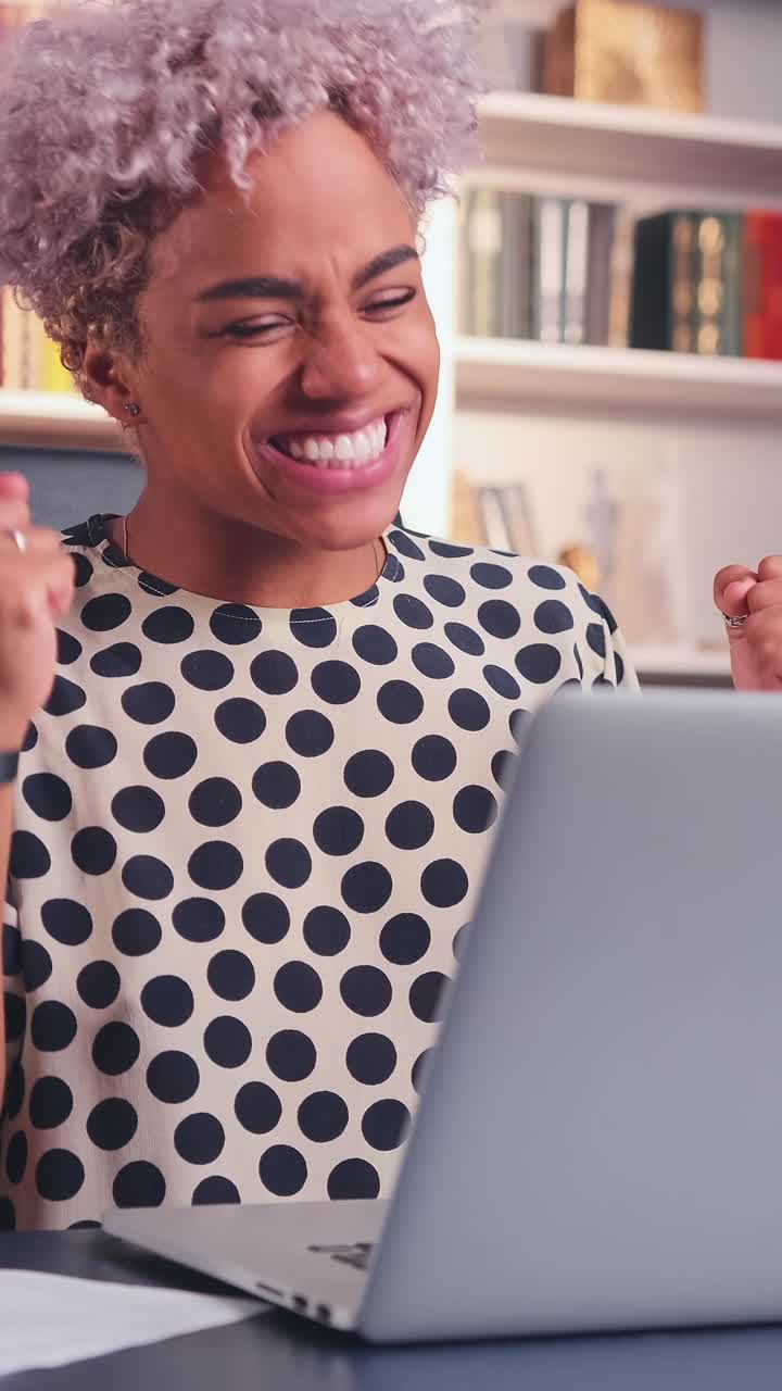 Young happy african american woman chatting via laptop sits at table in library