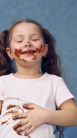 happy girl eating chocolate. portrait of happy girl eating chocolate bar and looking at camera