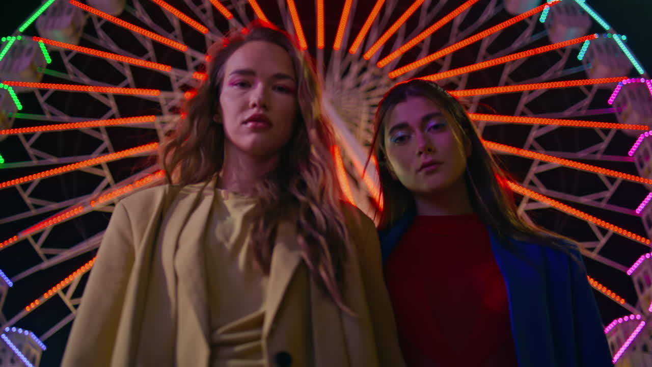 Splendide modelle in posa sulla giostra del luna park di notte in primo piano. Ragazze alla moda serie