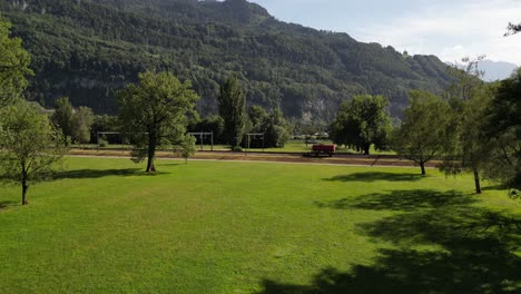 Fly-over-green-fields-in-farm-agriculture-local-people-region-in-pine-tree-forest-in-Switzerland-highlands-green-hills-in-the-village-and-tourists-accommodate-to-visit-Switzerland-nature-attractions