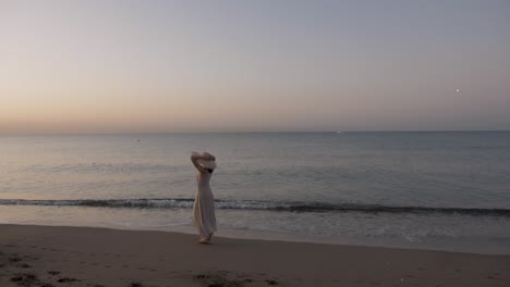 happy healthy romantic woman walking on the beach wearing dress and straw hat