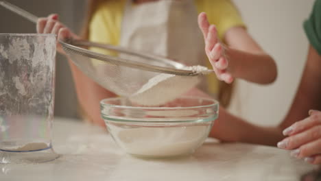 little girl sifting flour for baking