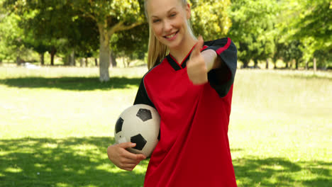 blonde football player smiling and giving thumbs up to camera