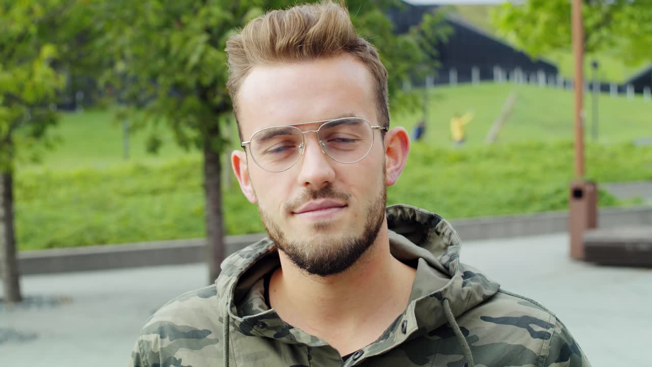 Ritratto di giovane uomo con gli occhiali che guarda la telecamera