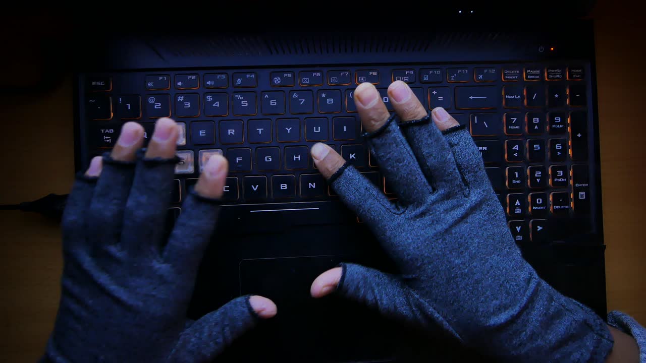 persona escribiendo en una computadora portátil con guantes