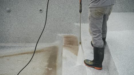worker power washes dirty pool steps before fiberglass pool installation