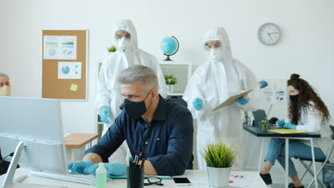 employees in protective gear working in an office during a pandemic