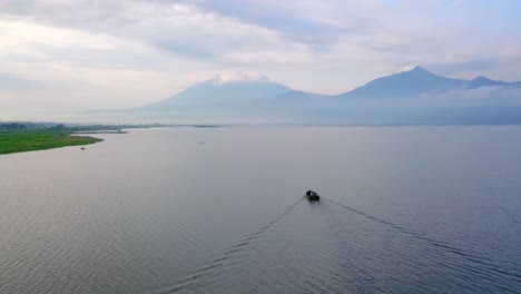 Vista-Aérea-De-Un-Solo-Barco-Que-Cruza-El-Lago-En-Un-Ambiente-Volcánico-Tropical-De-Indonesia