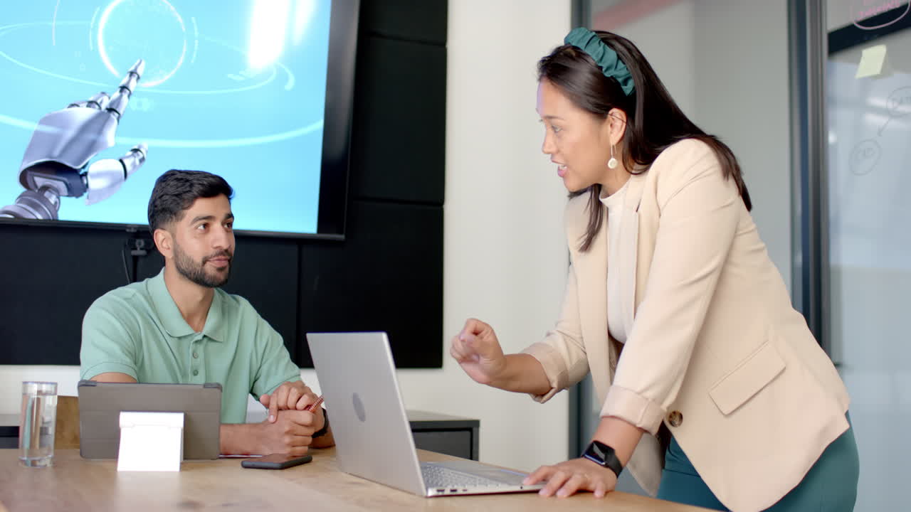 Discussing robotics project, colleagues collaborating with laptop in modern office