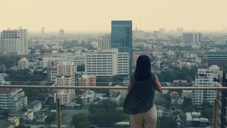 asian woman using smartphone while standing on the rooftop building.