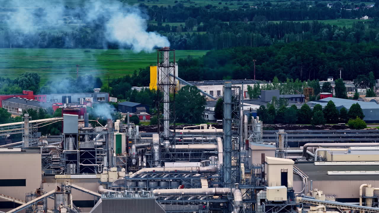 Aerial view of an active industrial plant releasing smoke above surrounding fields, highlighting manufacturing intensity and energy production within a rural landscape