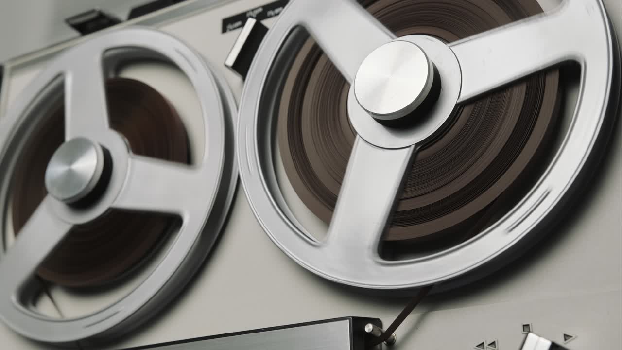 на катушке записывающего устройства играет катушка. вращающийся старинный музыкальный проигрыватель вблизи. ретро лента. вращающиеся катушки металлического цвета. вид сверху. популярные тенденции дискотеки 60-х, 70-х, 80-х, 90-х.