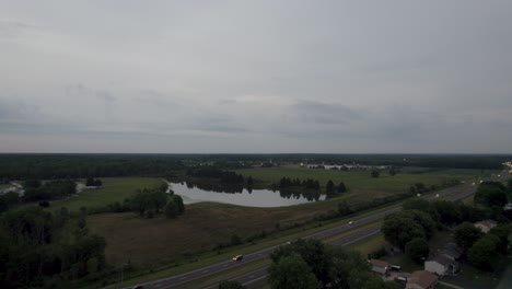 Eine-Drohnenaufnahme-Eines-Kleinen-Sees,-Der-Von-Bäumen-In-Einer-Stadt-Umgeben-Ist