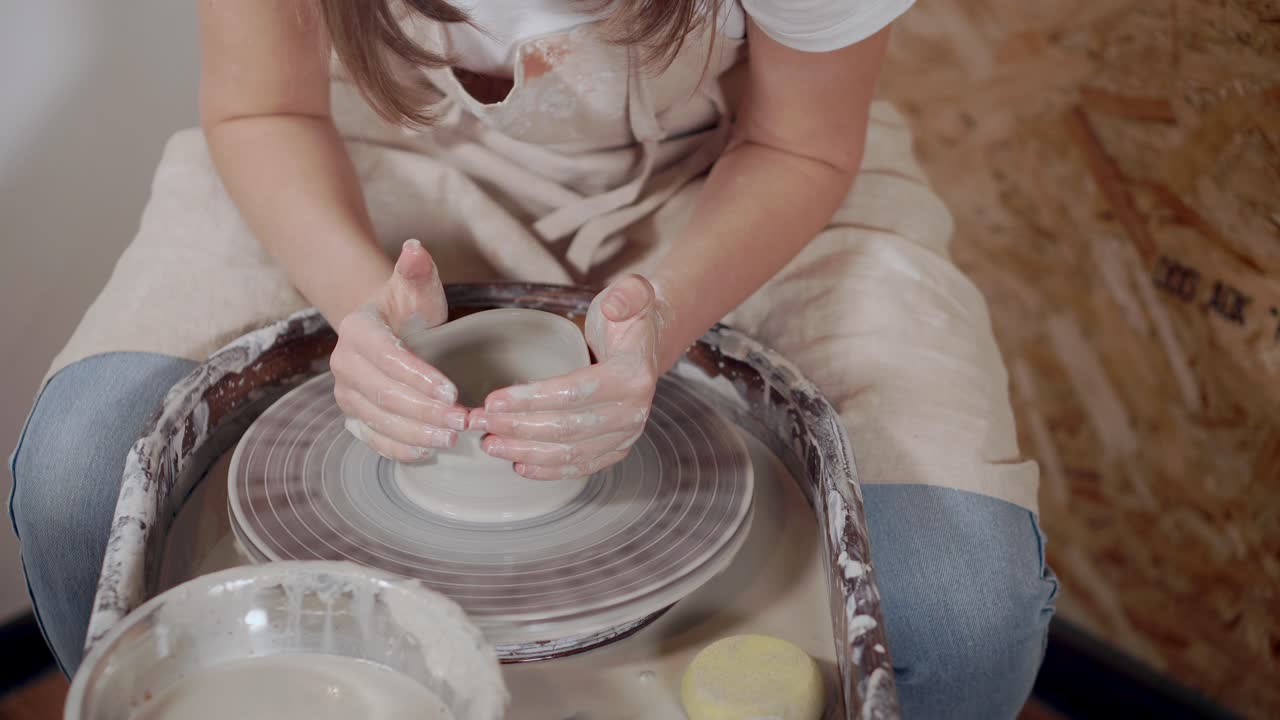 mujer moldeando arcilla en la rueda de cerámica