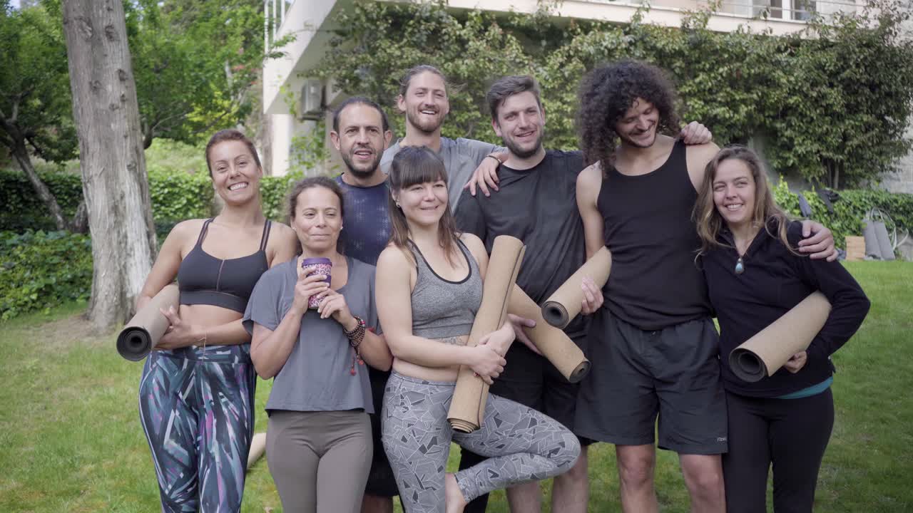 grupo de yoga sonriendo a la cámara al aire libre