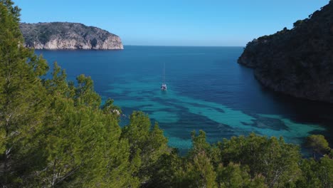 Pristine-beach-bay-clear-turquoise-water-with-trees-and-yacht-ship-sailing-boat-on-Palma-de-Mallorca-Island