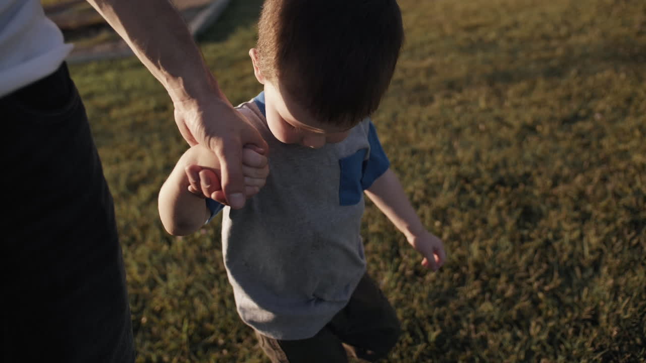 Pai e filho felizes de mãos dadas caminhando em câmera lenta cinematográfica