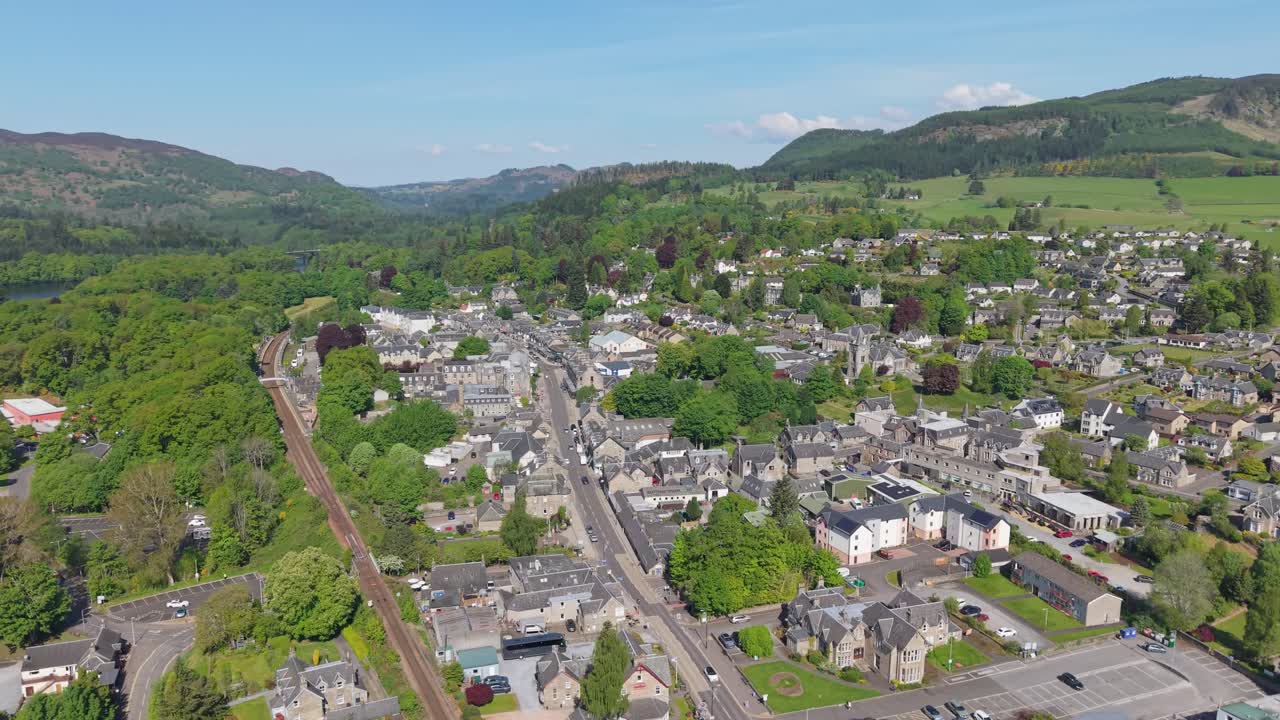 Orbit and aerial drone view of Pitlochry village in Scotland, showcasing its charming town, lush landscape, and surrounding highlands
