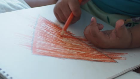 child drawing a triangle with crayon