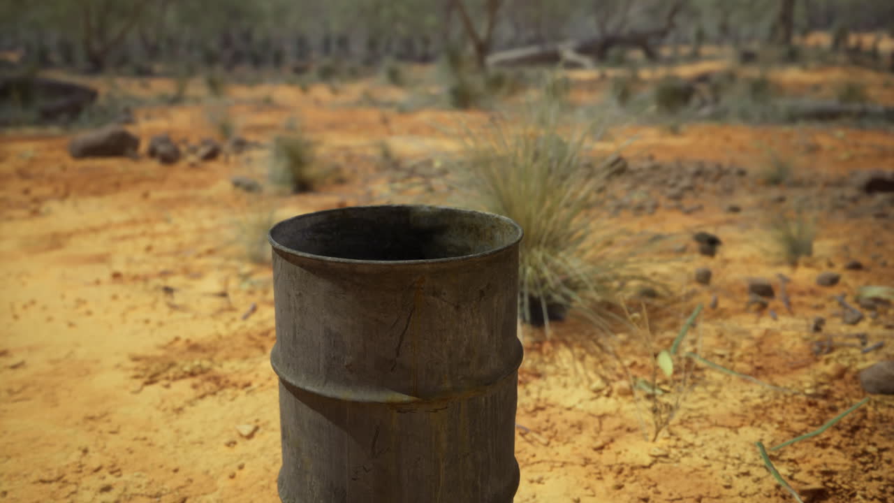 Rusty barrel amidst arid landscape with scattered rocks and sparse vegetation
