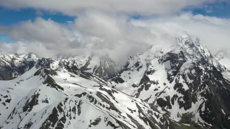 vuelo aéreo a través de nubes montañosas sobre hermosos picos nevados de montañas y glaciares.