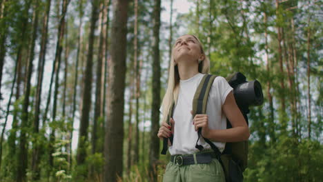 slow motion portrait: adult caucasian woman wearing shorts and t-shirt hikes through woods. young lady hiking