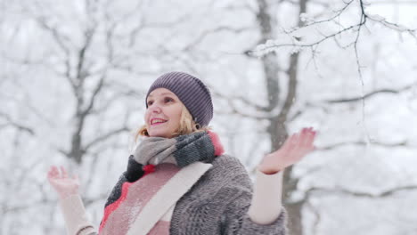 a young woman rejoices in the arrival of winter spins and catches snowflakes in the winter park