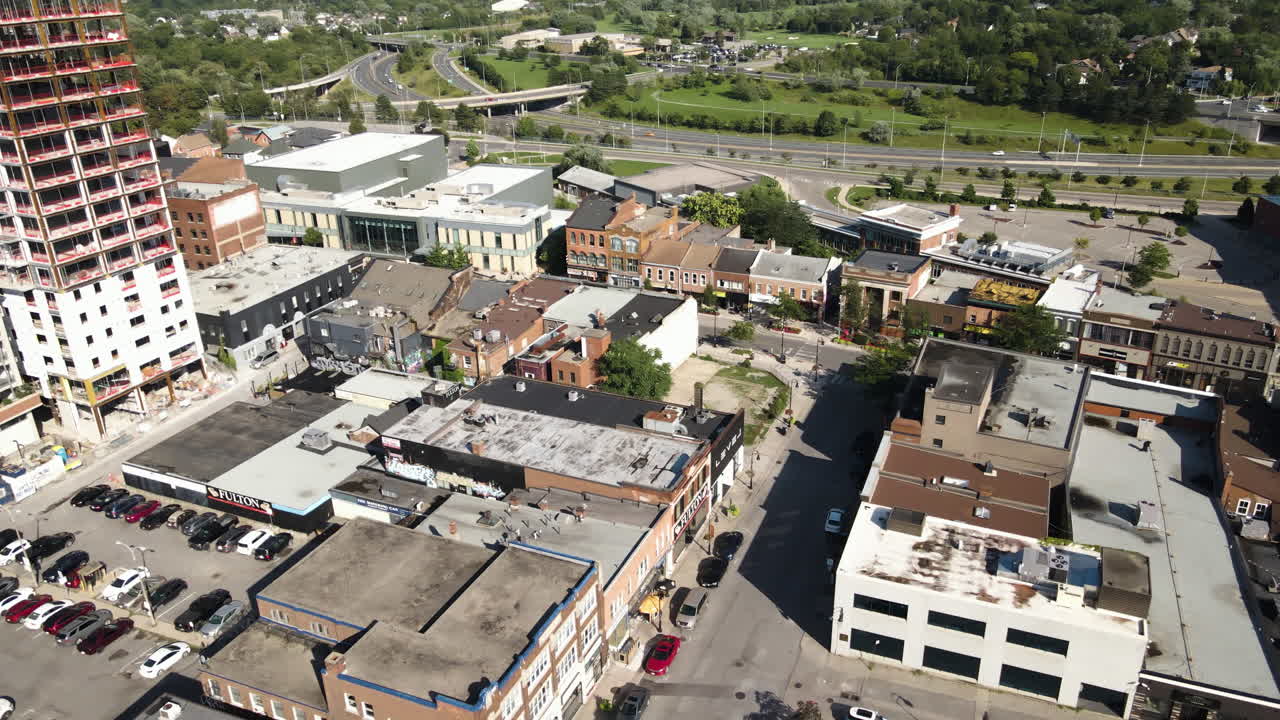 Slow bird's eye view drone dolly, growing urban scene with quaint main street shops off of highway offramp, canada