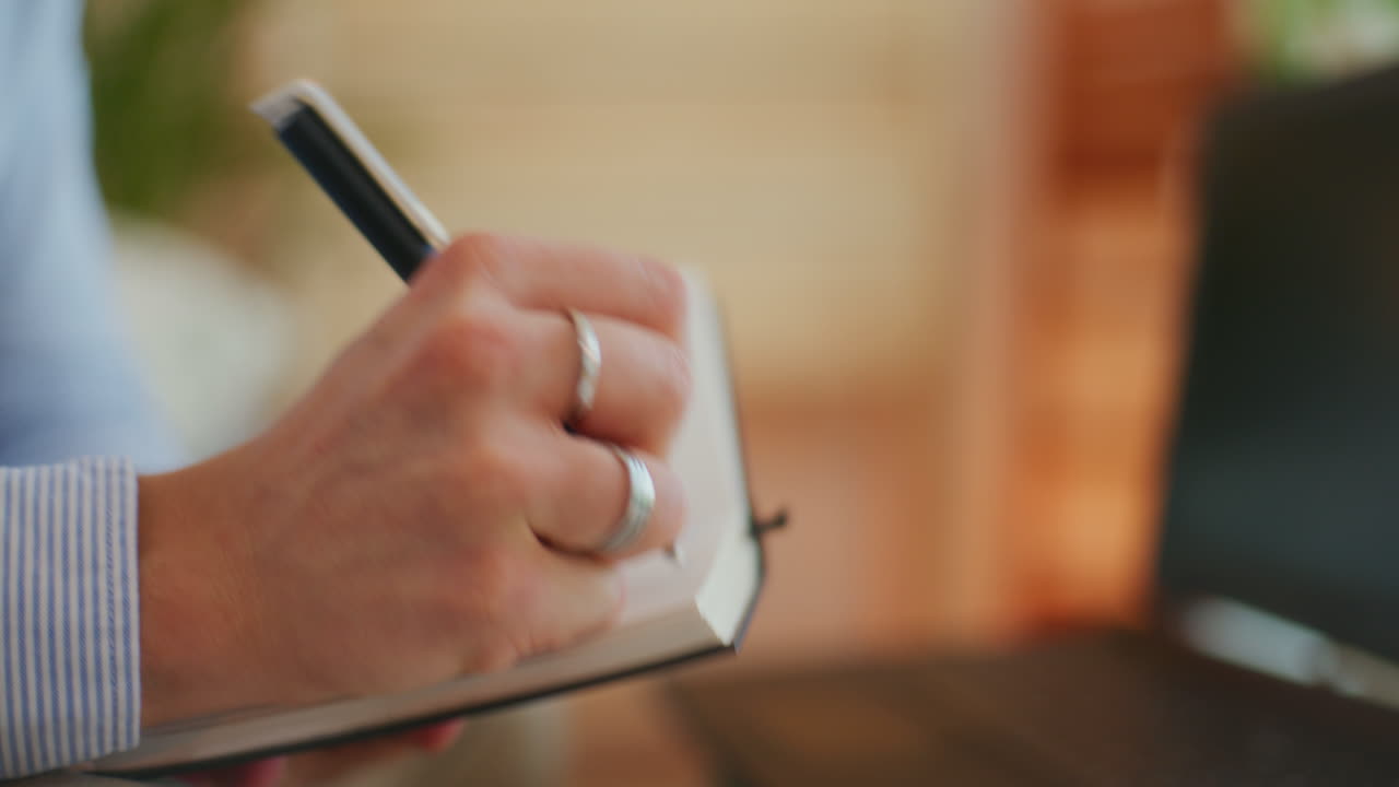 Man Notes Information in Notebook