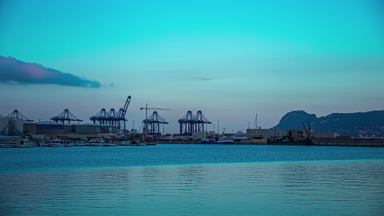 lapso de tiempo a través del puerto de algeciras durante el crepúsculo con vistas al puerto de envío de carga y grúas