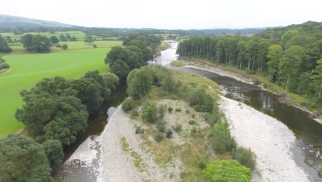 Wunderschöne-Drohnenaufnahmen,-Die-über-Einen-Von-Bäumen-Gesäumten-Flachen,-Langsam-Fließenden-Fluss-Und-Eine-Flussinsel-In-Der-Ländlichen-Landschaft-Des-Seengebiets,-Großbritannien,-Fliegen