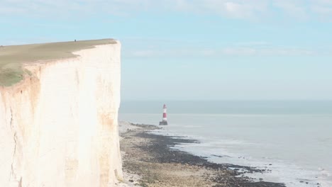 disparo de un dron a lo largo de enormes acantilados de tiza blanca abrigos del sur de inglaterra hacia el faro de beachy head