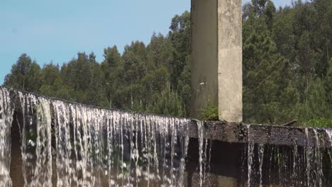 close up on some water falling from an artificial waterfall with some trees and the blue sky in the background