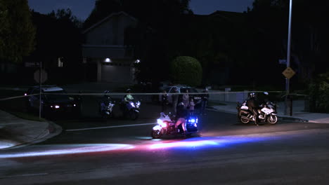 police block a road in an urban neighborhood at night